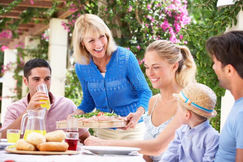 Hogere Vrouw die een Maaltijd van de Familie buiten dient stock foto's Hogere Vrouw die een Maaltijd van de Familie buiten dient stock foto's