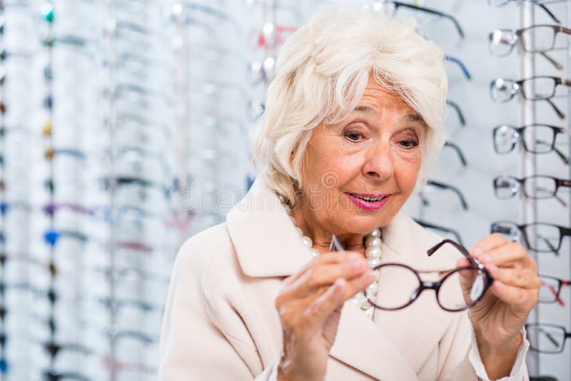 Hogere vrouw die op oogglazen proberen stock foto Hogere vrouw die op oogglazen proberen stock foto