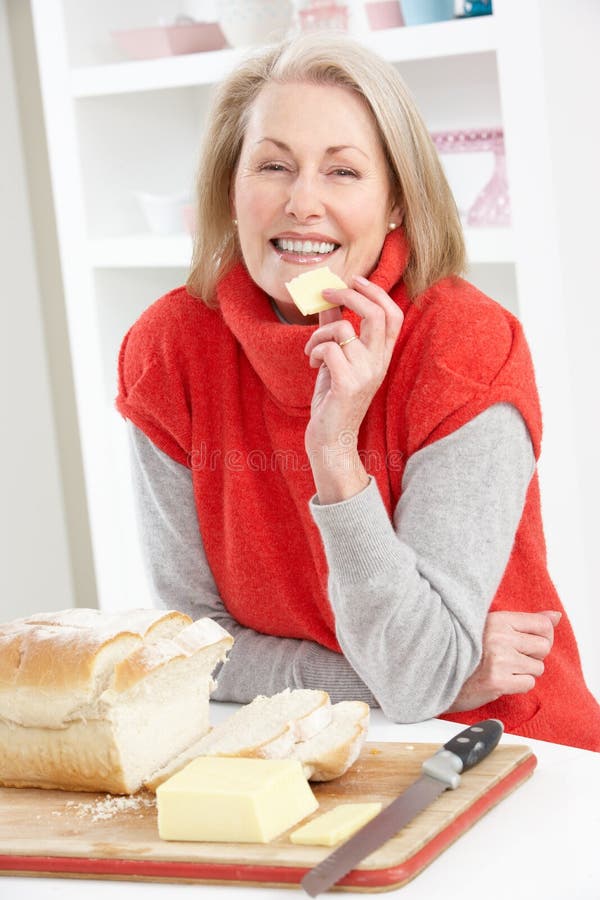 Hogere Vrouw die Sandwich in Keuken maakt stock foto Hogere Vrouw die Sandwich in Keuken maakt stock foto