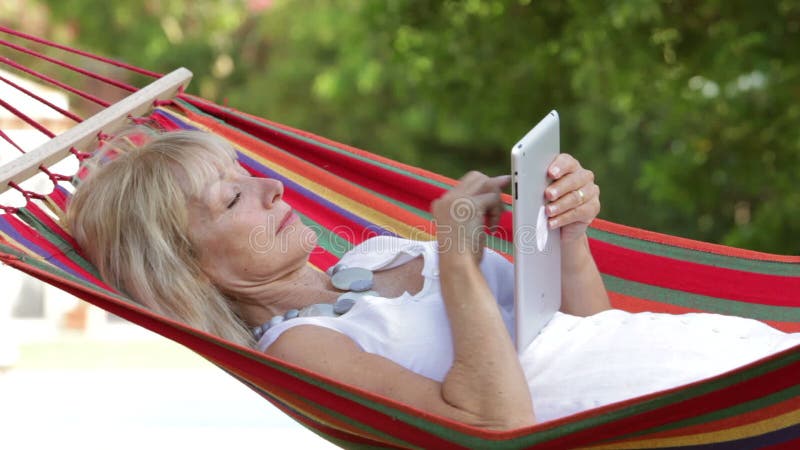 Hogere Vrouw in Hangmat die Tabletcomputer met behulp van