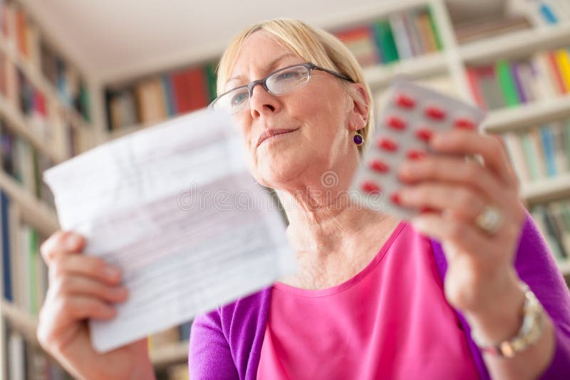Hogere vrouw met pillen en voorschrift stock fotografie Hogere vrouw met pillen en voorschrift stock fotografie