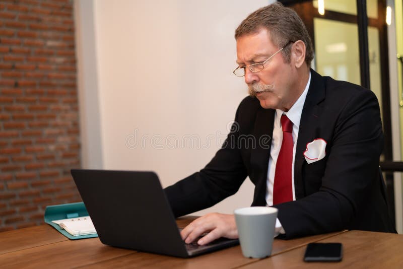 Hogere zakenman die met laptop in het zolderbureau werken stock afbeelding Hogere zakenman die met laptop in het zolderbureau werken stock afbeelding