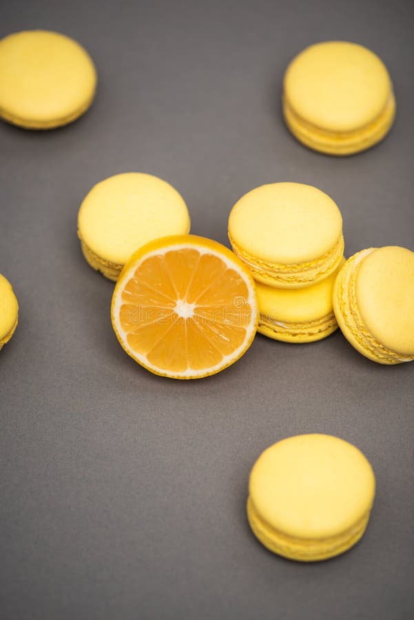 Hohe Winkelsicht von leckeren gelben macarons fast die Hälfte der kolossale Zitrone auf grauem Hintergrund. lizenzfreies stockbild