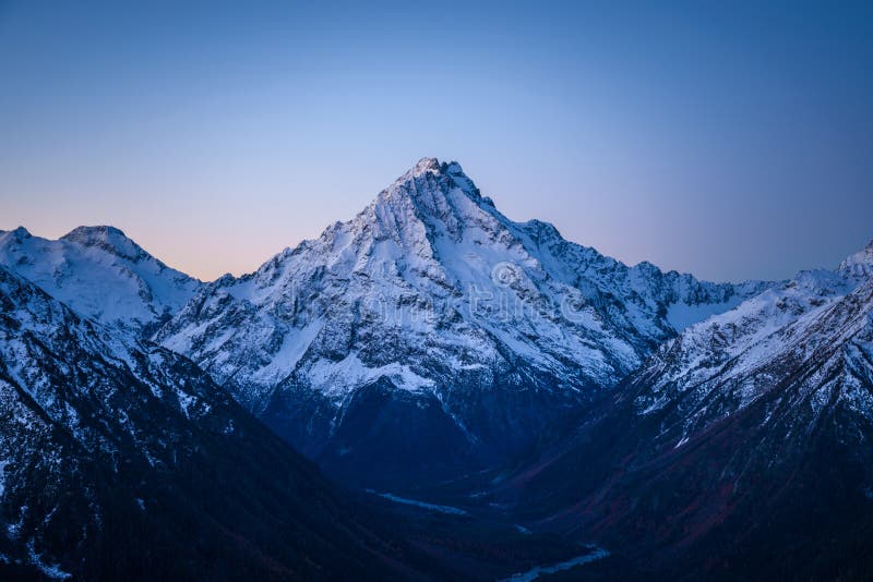 High snow-covered mountain just after sunset. Cold dark autumn mountain view. Cloudless clear sky. High snow-covered mountain just after sunset. Cold dark autumn mountain view. Cloudless clear sky