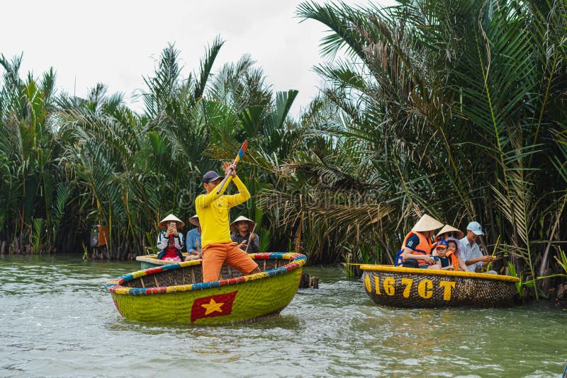 A Vietnamese man is dancing on colorful basket boat