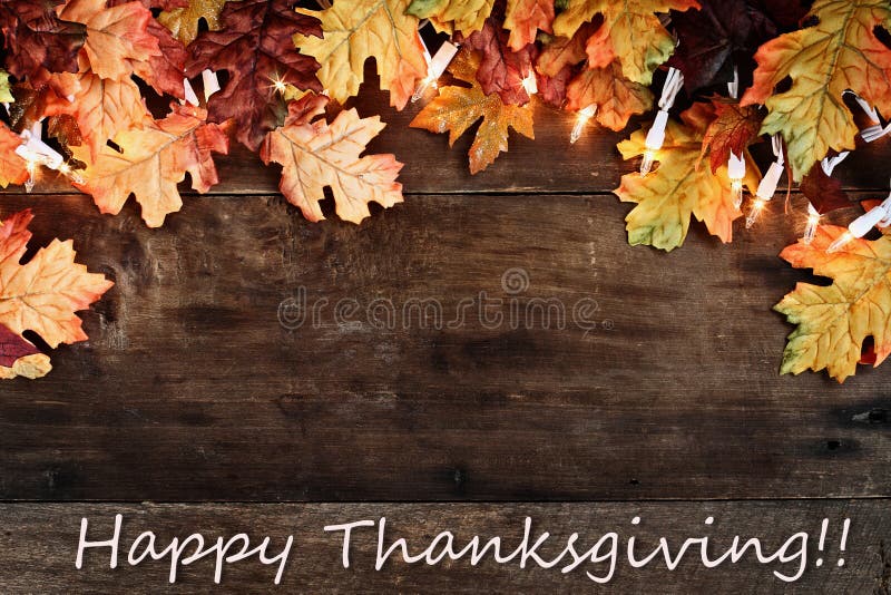 Rustic fall background of autumn leaves and decorative lights with Happy Thanksgiving text over a rustic background of barn wood. Image shot from overhead. Rustic fall background of autumn leaves and decorative lights with Happy Thanksgiving text over a rustic background of barn wood. Image shot from overhead.