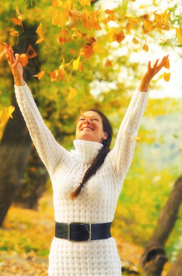 Hojas de otoño de la muchacha que lanzan en el aire fotos de archivo libres de regalías Hojas de otoño de la muchacha que lanzan en el aire fotos de archivo libres de regalías