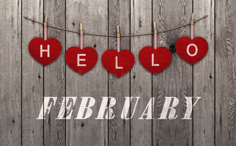 Hola febrero escrito en el colgante de corazones rojos y del viejo fondo de madera