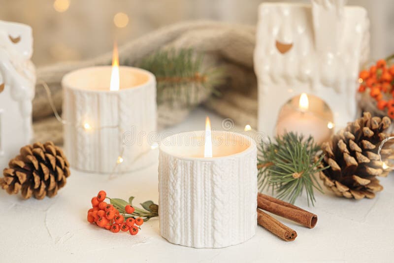 Holders with burning candles and decoration on table against blurred Christmas lights