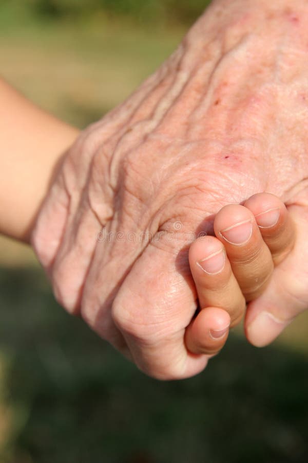 Un 3-anno-vecchia ragazza e un signore di 92 anni la donna si tengono per mano.