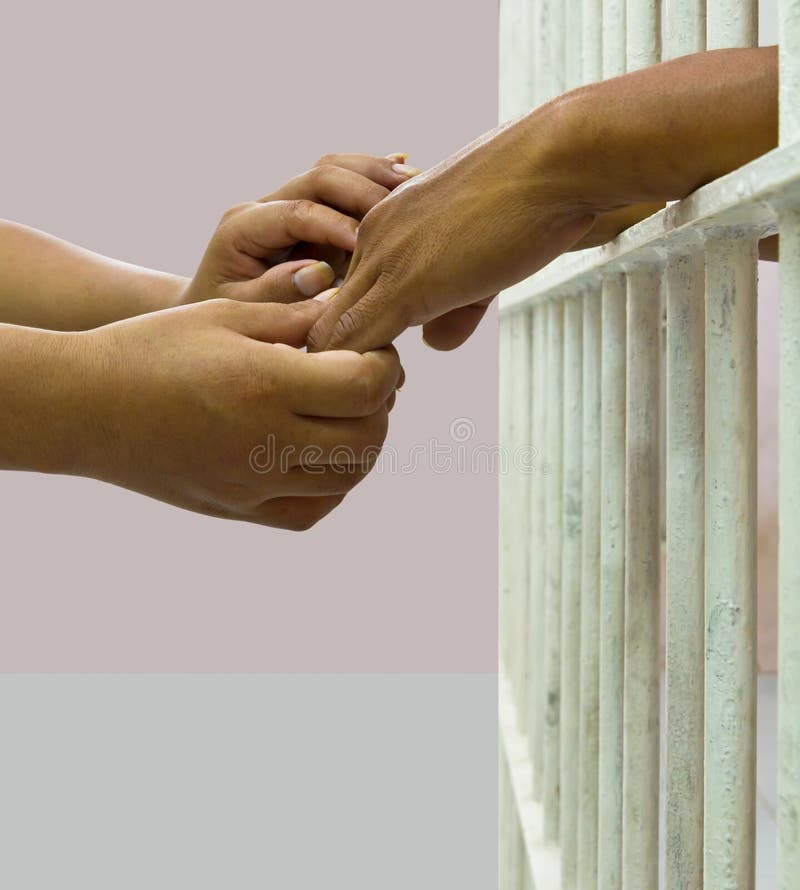 Woman comforting man in prison by holding his hand gently