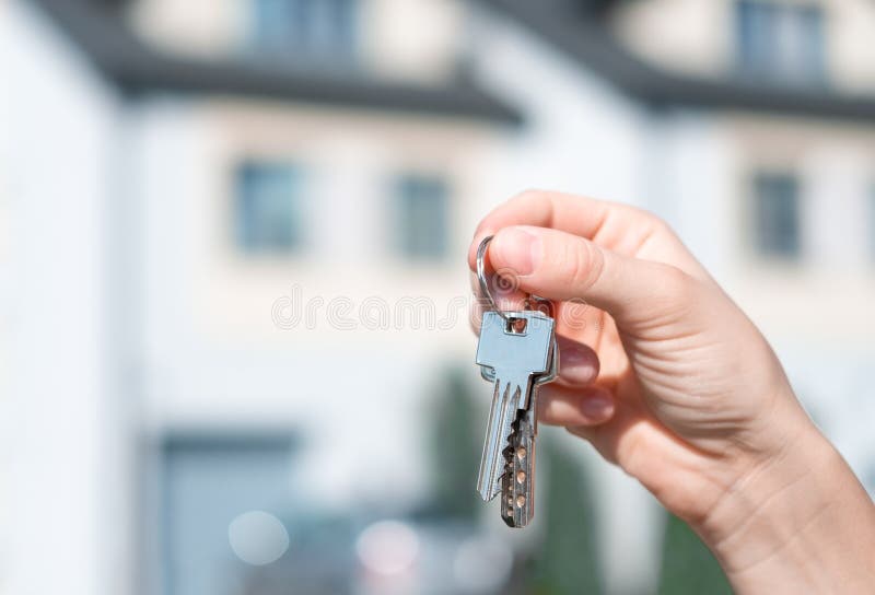 Holding house keys front of a new home. Keys on the background of the house. stock photography