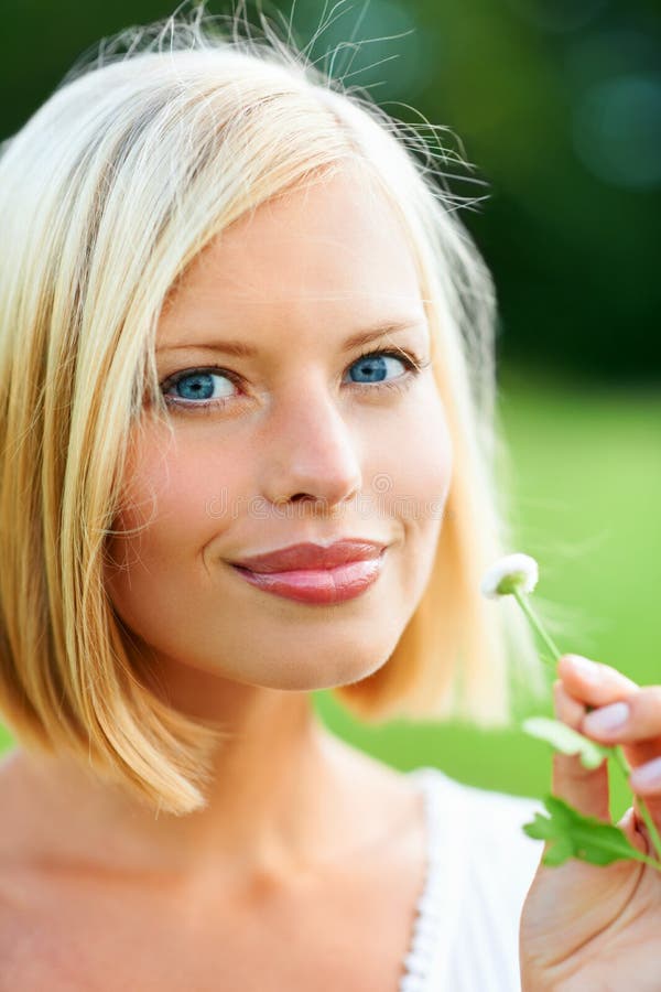 Holding natural beauty in her hands. Beautiful young woman holding a tiny flower outdoors.