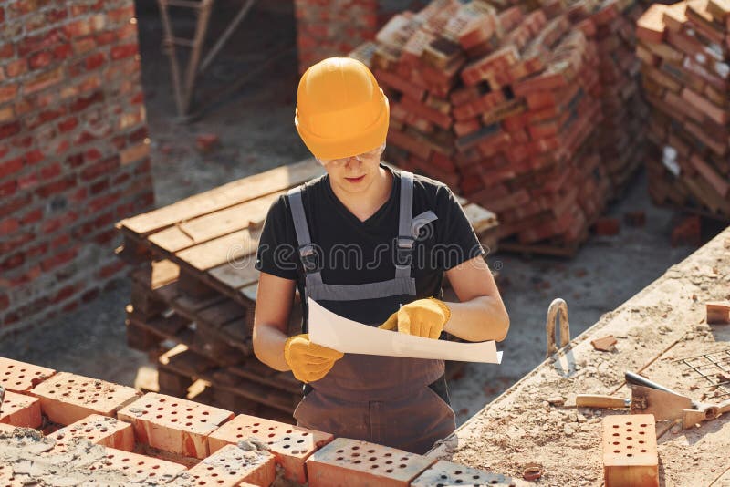 Holding Plan in Hands. Construction Worker in Uniform and Safety