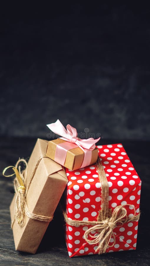 Holiday boxes Packed in crafting paper and red polka dots on dark wooden background. Cards with gifts and place for text.