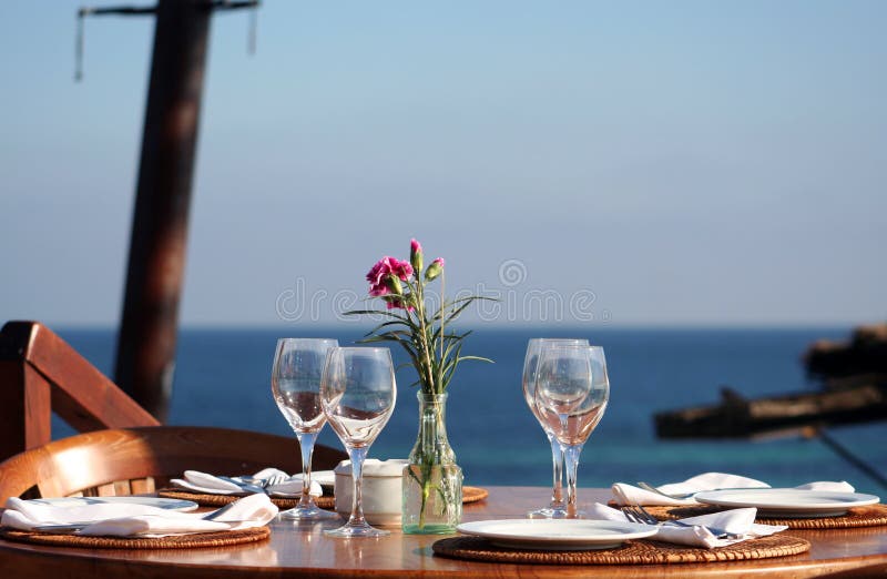 Pranzo o cena al tavolo vicino al mare e in colori caldi.