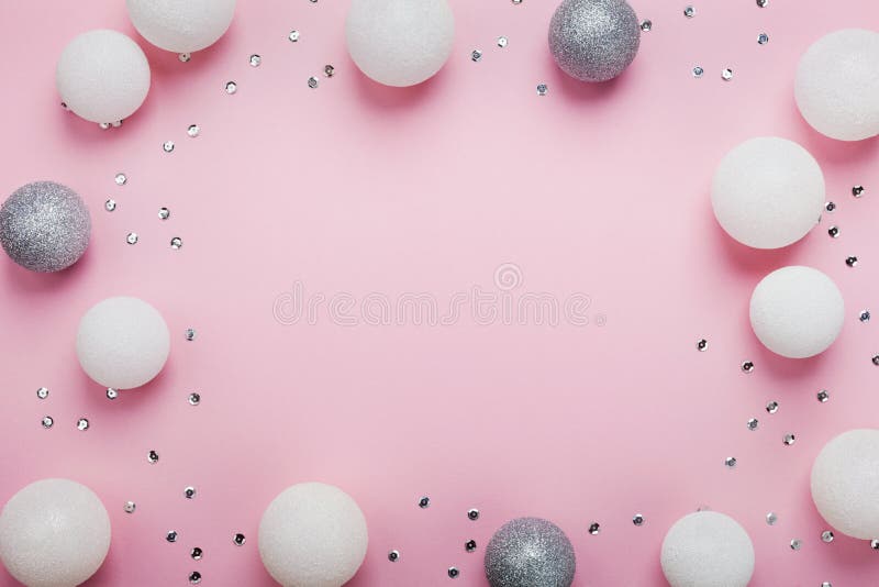 Holiday frame made of christmas balls and sequins on stylish pink table top view. Fashion background. Flat lay style. Party mockup.