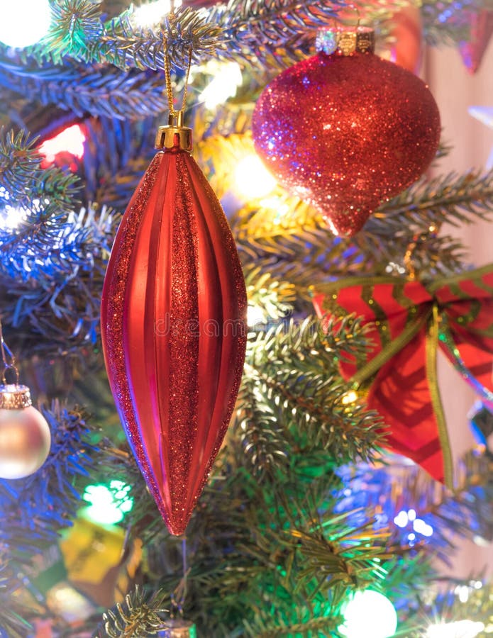 Holiday season, christmas tree decorations glow under luminous and vivid, colorful lights on a small faux indoor tree. Bursting, ball.