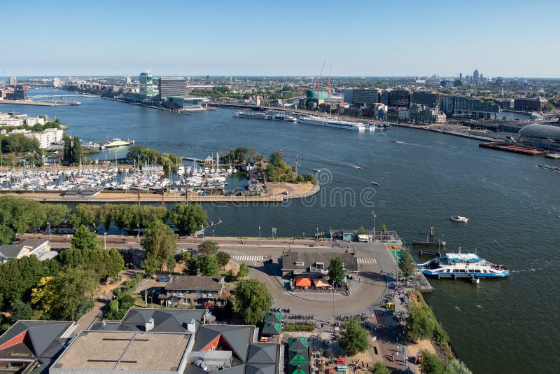 Holländsk hamn Amsterdam för sikt med marina, färjan och hyreshusar arkivfoto