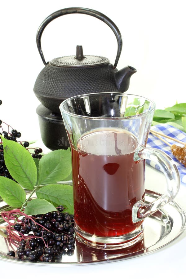 A glass of elderberry tea with fresh elderberries. A glass of elderberry tea with fresh elderberries