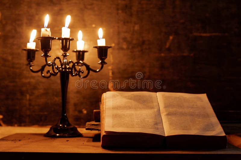 Open Holy Bible and candle on a old oak wooden table. Beautiful gold background. Religion concept