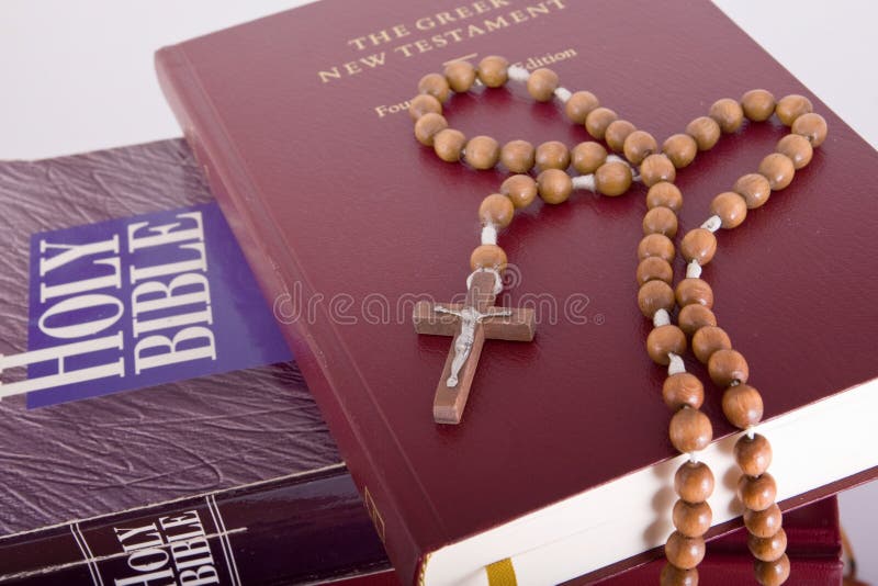 Holy Bible with rosary on pile of old books