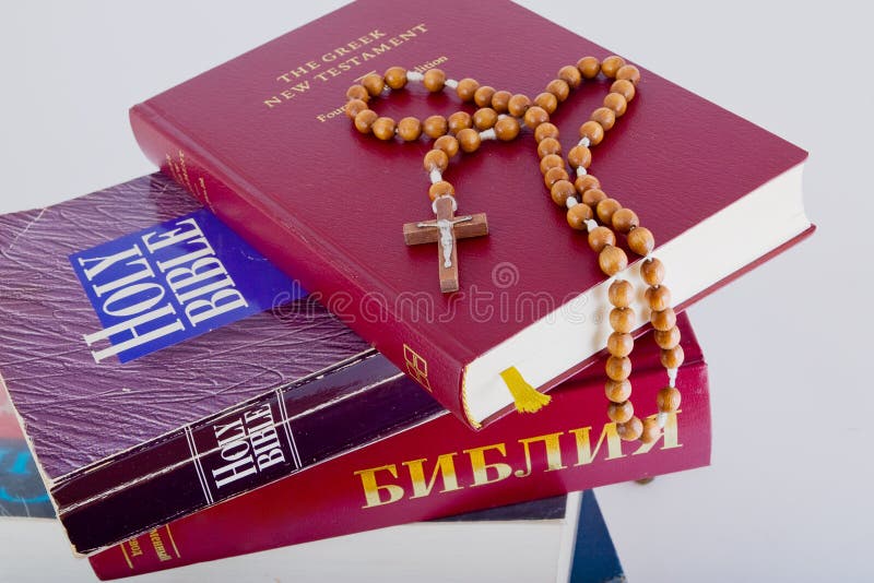 Holy Bible with rosary on pile of old books