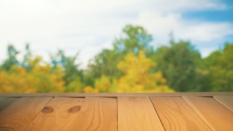 Holztisch auf farbenfrohen, verschwommenen Herbstuntergründen mit blauem Himmel und gelber Baumfoilage stock video