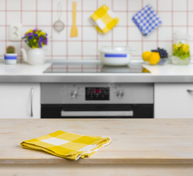 Holztisch mit gelber Serviette auf Küchenhintergrund lizenzfreie stockfotos Holztisch mit gelber Serviette auf Küchenhintergrund lizenzfreie stockfotos