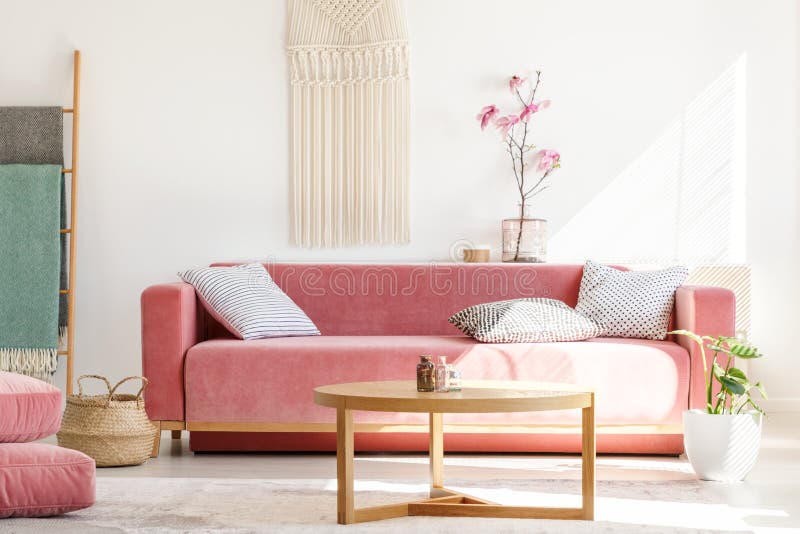 Holztisch vor rotem Sofa im Pastellwohnzimmerinnenraum