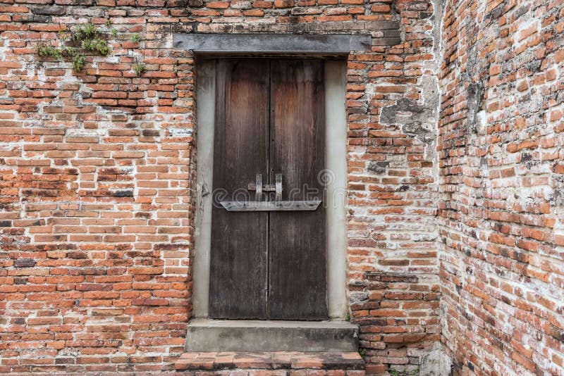 Traditional Thai wooden door on old brick wall of antique Ayutthaya Historic park temple, Thailand. Closeup textured pattern background. Traditional Thai wooden door on old brick wall of antique Ayutthaya Historic park temple, Thailand. Closeup textured pattern background.