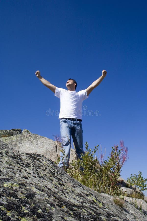 Successful man in the mountain with hands raised up and white T-Shirt. Space for text available. Successful man in the mountain with hands raised up and white T-Shirt. Space for text available.