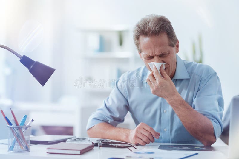 Hombre adulto agradable que usa un tejido de papel fotos de archivo Hombre adulto agradable que usa un tejido de papel fotos de archivo
