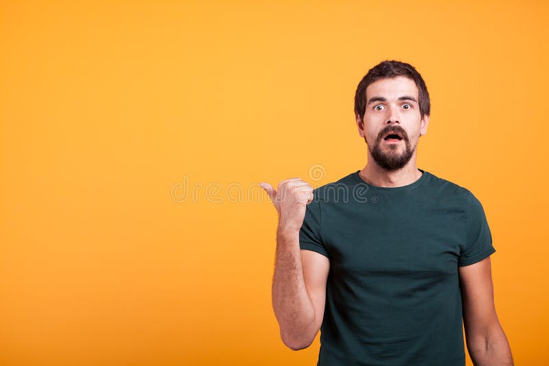 Hombre adulto emocional sorprendido que señala en el copyspace imagen de archivo libre de regalías Hombre adulto emocional sorprendido que señala en el copyspace imagen de archivo libre de regalías