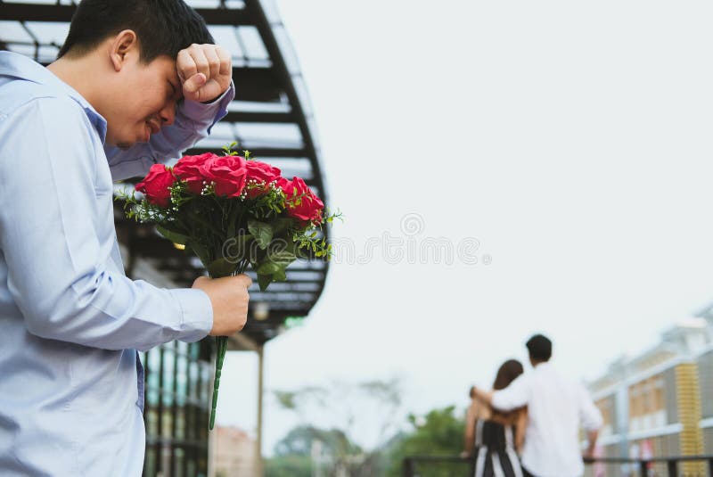 Hombre afligido que sostiene el ramo de rosas rojas que sienten tristes mientras que s fotografía de archivo libre de regalías Hombre afligido que sostiene el ramo de rosas rojas que sienten tristes mientras que s fotografía de archivo libre de regalías
