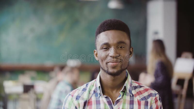 Hombre africano hermoso en la oficina moderna ocupada Retrato del varón acertado joven que mira la cámara y la sonrisa imagen de archivo Hombre africano hermoso en la oficina moderna ocupada Retrato del varón acertado joven que mira la cámara y la sonrisa imagen de archivo