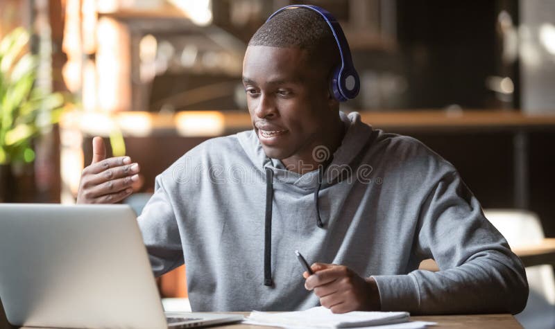 Hombre afroamericano con auriculares haciendo videollamadas en un cafÃ©