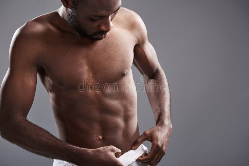 Hombre afroamericano hermoso joven que ajusta su toalla