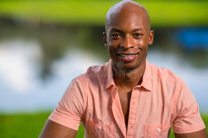 Hombre afroamericano joven hermoso del retrato que sonríe en la cámara Hombre que lleva un medio camino desabrochado camisa rosad foto de archivo Hombre afroamericano joven hermoso del retrato que sonríe en la cámara Hombre que lleva un medio camino desabrochado camisa rosad foto de archivo