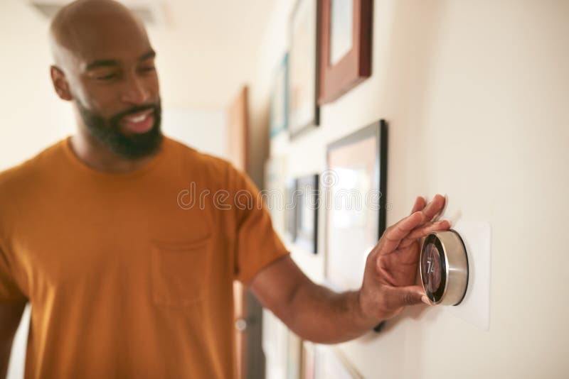 Hombre ajustando el termostato de calefacción central digital en casa