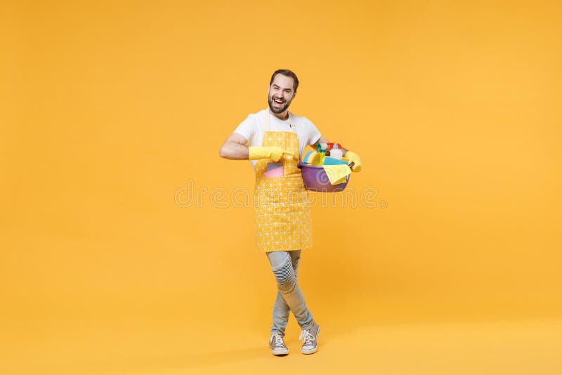 Hombre alegre ama de casa en guantes de goma de manzana haciendo tareas domésticas aisladas en fondo amarillo. concepto de limpiez imágenes de archivo libres de regalías
