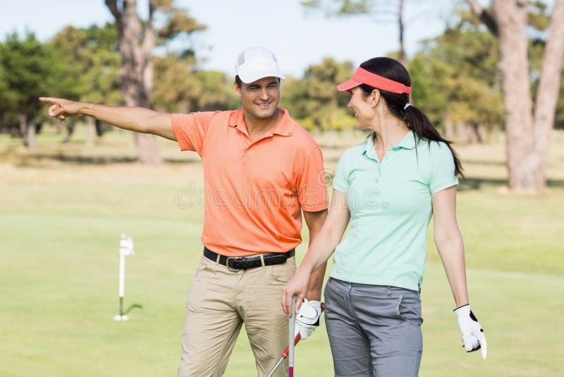 Hombre alegre del golfista que señala mientras que hace una pausa a la mujer foto de archivo Hombre alegre del golfista que señala mientras que hace una pausa a la mujer foto de archivo