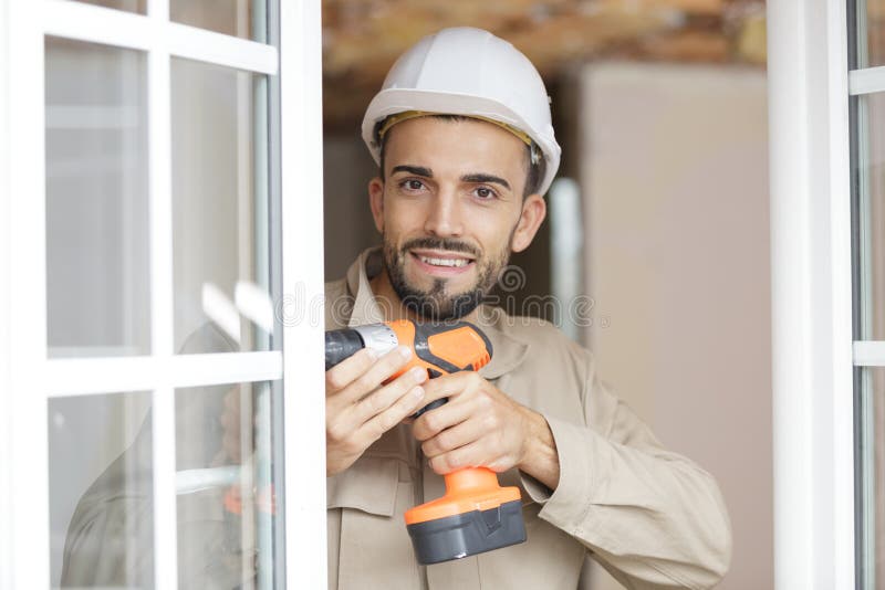Hombre alegre y constructor usando taladro imagenes de archivo