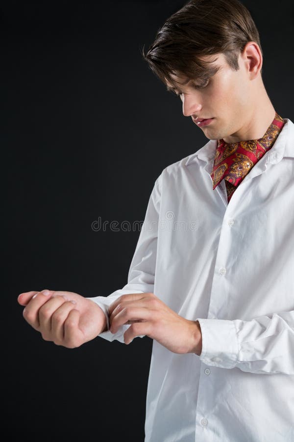 Hombre andrógino que abotona su manga de la camisa foto de archivo Hombre andrógino que abotona su manga de la camisa foto de archivo