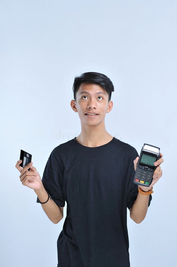 Hombre asiático joven que muestra una tarjeta de crédito/una tarjeta de débito y una recogida de datos electrónicos y un x28; EDC imágenes de archivo libres de regalías Hombre asiático joven que muestra una tarjeta de crédito/una tarjeta de débito y una recogida de datos electrónicos y un x28; EDC imágenes de archivo libres de regalías