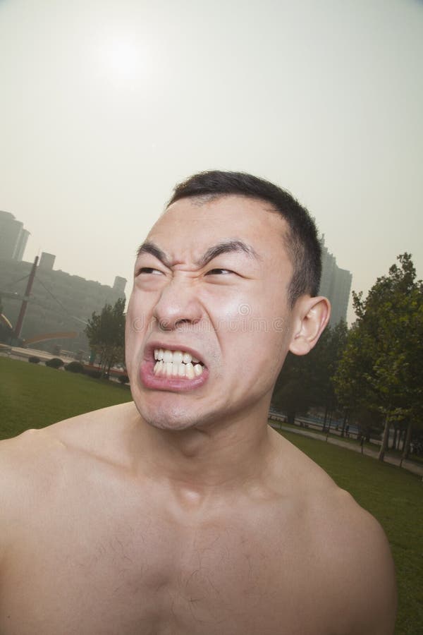 Hombre atlético joven descamisado que gruñe al aire libre en un parque en Pekín imagen de archivo libre de regalías Hombre atlético joven descamisado que gruñe al aire libre en un parque en Pekín imagen de archivo libre de regalías