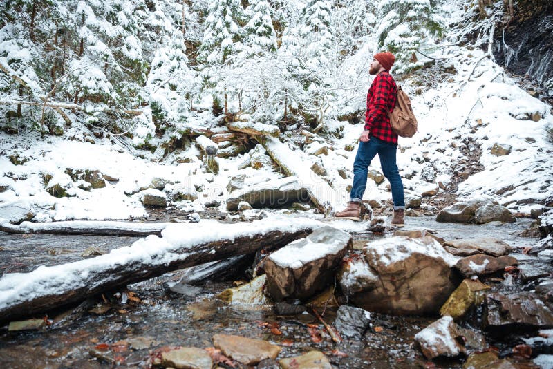 Hombre barbudo atractivo que se coloca cerca del río en bosque del invierno fotografía de archivo Hombre barbudo atractivo que se coloca cerca del río en bosque del invierno fotografía de archivo