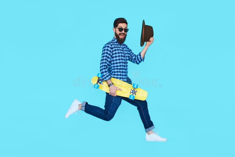 Hombre barbudo bastante joven que salta con el monopatín amarillo imagen de archivo Hombre barbudo bastante joven que salta con el monopatín amarillo imagen de archivo