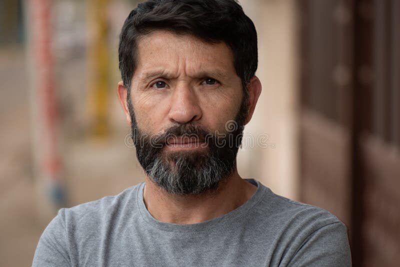 Hombre barbudo de cabello negro con una mirada seria que resalta las arrugas en su cara con el ceño imagenes de archivo