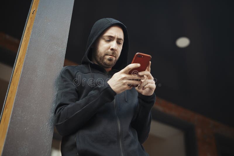 Hombre barbudo que se coloca al lado de los posts concretos y que mira fijamente la pantalla foto de archivo libre de regalías Hombre barbudo que se coloca al lado de los posts concretos y que mira fijamente la pantalla foto de archivo libre de regalías